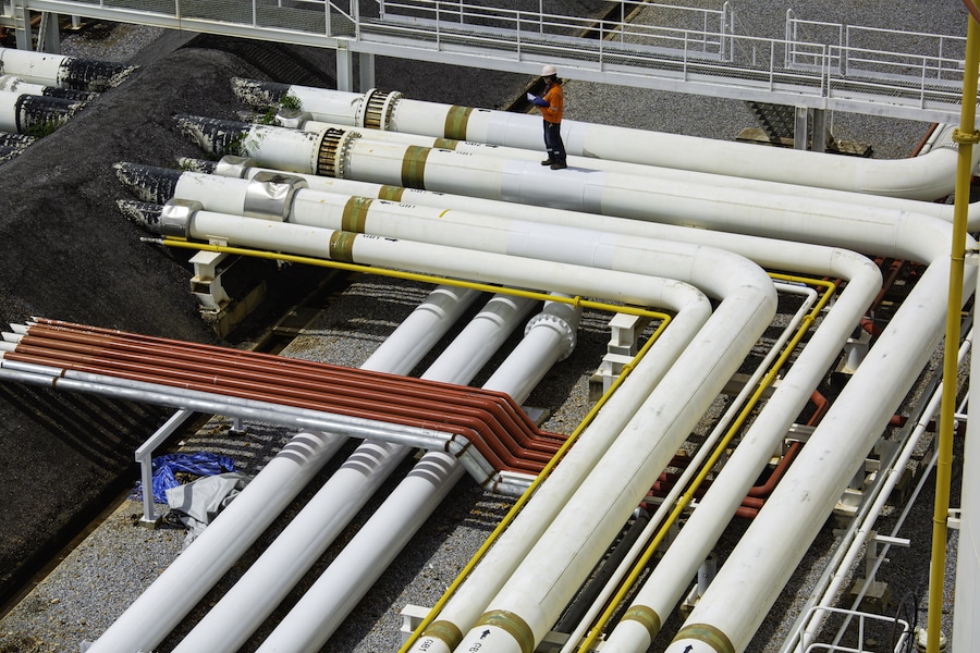 top-view-male-worker-inspection-steel-long-pipes-pipe-elbow-station-oil-factory-refinery-valve-visual-check-record-pipeline-oil